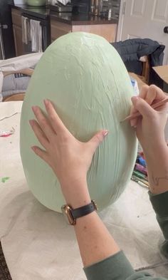 a woman is working on an object in the process of painting it with her hands