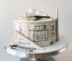 a cake that is on top of a table with some scissors and pencils next to it