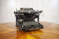 an old fashioned typewriter sitting on top of a wooden table