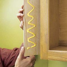 a person holding up a wooden box with a hot dog on it's side