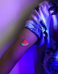 a woman's arm with a watermelon tattoo on the left side of her arm