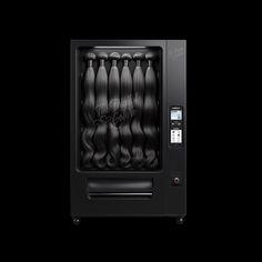 the hair machine is black and has long wavy hair in it's display case