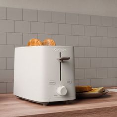 a toaster sitting on top of a wooden counter next to a plate of bread