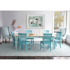 a dining room table with blue chairs and a painting on the wall in the background