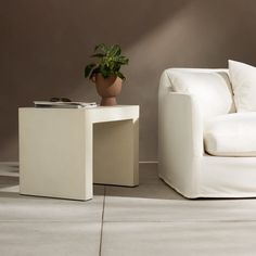 a white chair sitting next to a table with a potted plant on it