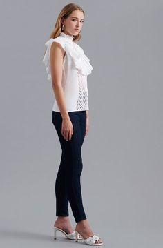 The CENITZ is an eyelet top featuring a mock ruffle neck and a ruffle bib detail on the front yoke, along with a center front button placket for closure. The light eyelet cotton fabric is durable but soft, making it ideal for wearing in warmer temperatures all year round. White embroidered shirt with ruffle cap sleeves Center front button placket for closure This top is made of embroidered open eyelet cotton Body: 100% Cotton; Side Panels: 92% Cotton, 8% Elastane Lightweight and airy, this fabri