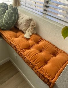 a window sill with pillows on it and a stuffed animal sitting on the pillow