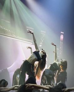 dancers on stage with their arms in the air