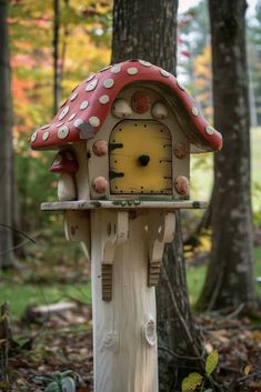 a bird house with a red roof and white polka dots on it in the woods