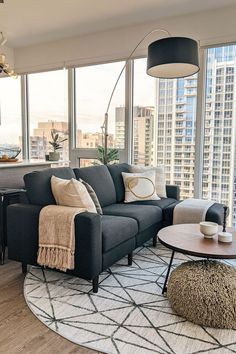 a living room filled with furniture next to large windows and a rug on the floor