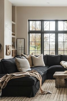 a living room filled with lots of furniture next to a large window covered in blankets