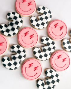 some decorated cookies with pink icing and black and white checkerboard designs on them