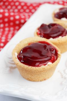 three small desserts on a white plate sitting on a red and white tablecloth