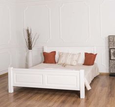 a white bed sitting on top of a hard wood floor next to a wall mounted clock