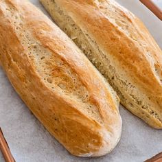 two loaves of bread sitting on top of a piece of wax paper next to each other