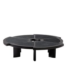 a black table with four legs and a circular design on the top, sitting in front of a white background