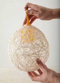 a hand holding a string ball with an ornament hanging from it's side