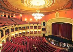 an auditorium with red seats and chandelier