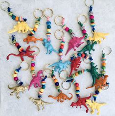 a bunch of key chains that have different colored dinosaurs on them