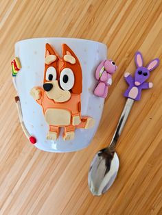 a cup that is sitting on the floor next to a spoon and some toy animals