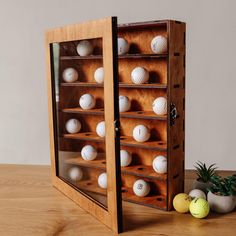 a wooden case with many balls in it on a table next to a potted plant