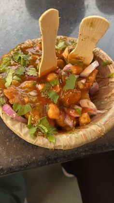 a wooden spoon sticking out of a bowl filled with food on top of a table