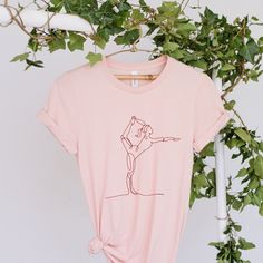 a pink t - shirt with an image of people on it hanging from a tree