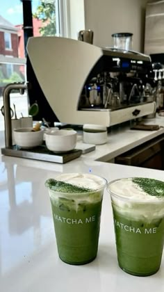 two green drinks sitting on top of a counter