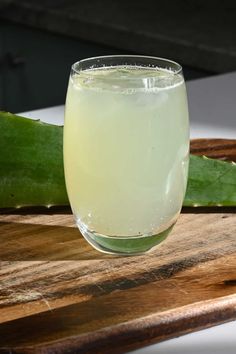 a close up of a wine glass on a wooden table with aloei in the background