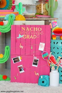 a pink sign that says nacho average grad next to cactus decorations and pictures