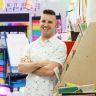 a man is standing in front of some art supplies