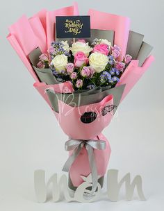 pink and white flowers are wrapped in grey paper