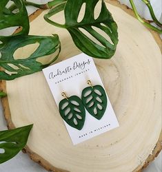 the green leaf earrings are next to a plant