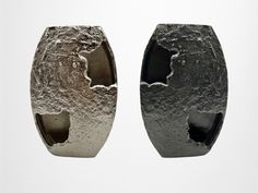 two silver vases sitting side by side on top of a white surface with holes in the middle