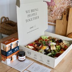 an open box of food sitting on top of a wooden table next to boxes of condiments