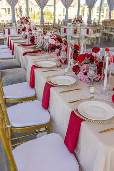 the tables are set with white and red linens, gold rimmed place settings, and pink flowers