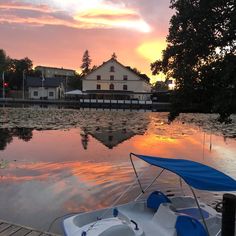 a boat is sitting on the water at sunset in front of a house and dock