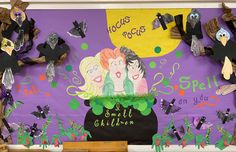 a bulletin board decorated with paper dolls and witches on it's purple wall, surrounded by halloween decorations