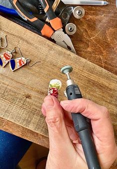 a person is working on some earrings with scissors and pliers in the back ground