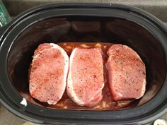 three raw pork chops in a slow cooker