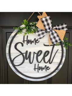 a sign that says home sweet home hanging on a door with greenery around it