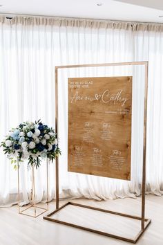 a wedding seating chart with flowers and greenery in front of a white curtained window