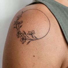 a woman with a tattoo on her shoulder has flowers growing out of the back of her shoulder