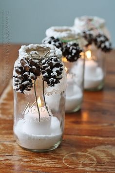 pine cones and candles are in mason jars with snow on them, sitting on a table