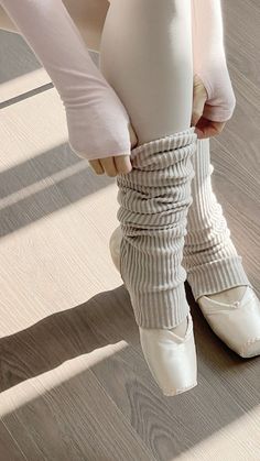 the legs and feet of a ballerina in white ballet shoes, with their arms wrapped around each other