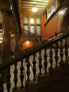 an ornate staircase with wooden balconies and railings in front of a stained glass window