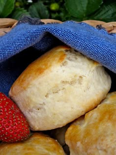 strawberries and rolls in a wicker basket with blue cloth on the table outside