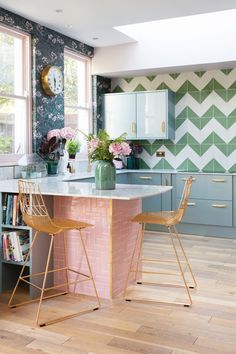 a kitchen with green and white wallpaper, gold bar stools