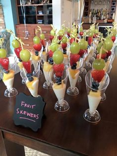 fruit skewers are arranged in wine glasses on a table