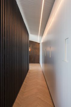 the hallway is lined with black slats and white walls, along with wood flooring